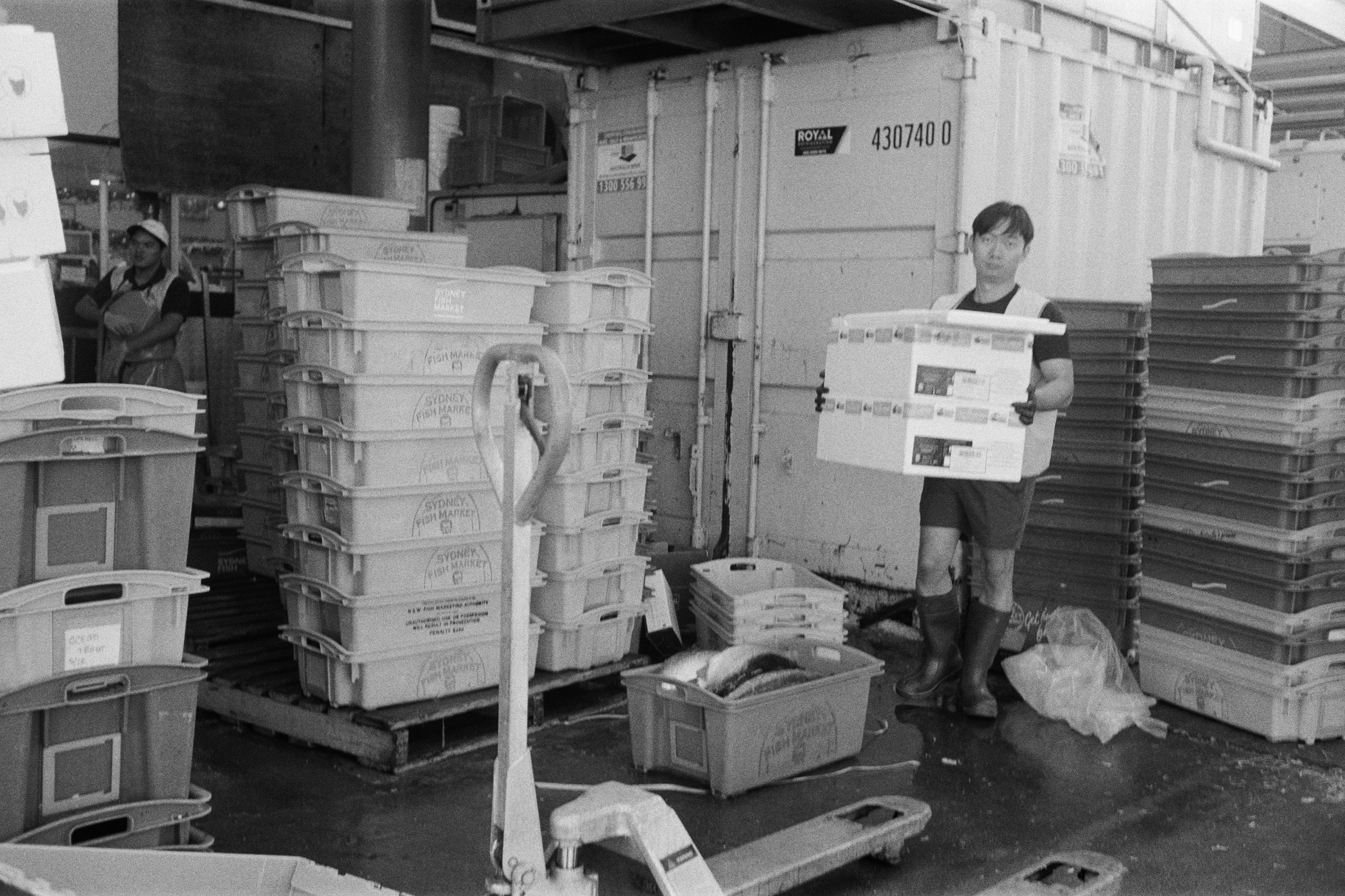 A worker ferrying fish from the refrigerators outside to the counters inside.